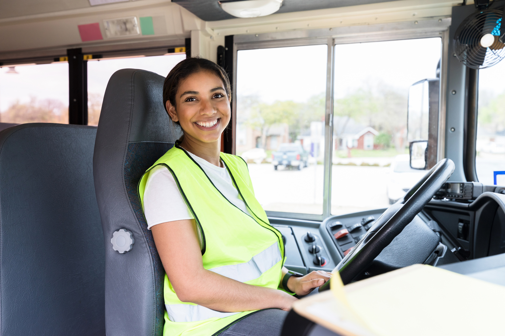 Cheerful, mid adult female school bus driver smiles for camera